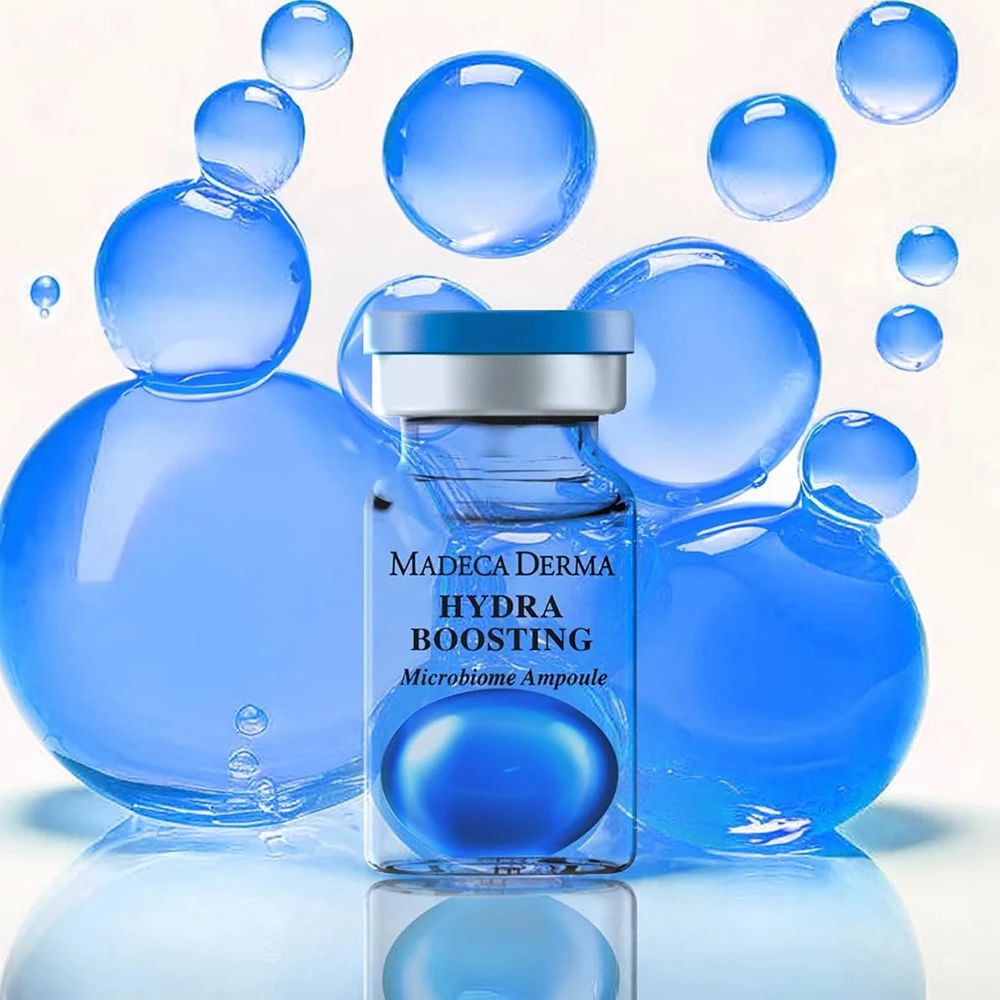 Glasampulle mit blauem Serum. Beschriftung: Madeca Derma Hydra Boosting Microbiome Ampulle. Hintergrund: blaue Kugeln.