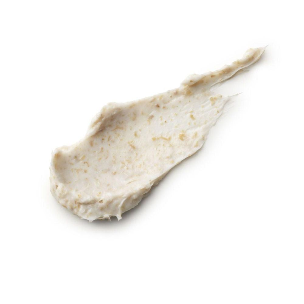 Ausgestrichene Creme mit sichtbaren Partikeln. Helle Farbe, auf weißem Hintergrund.