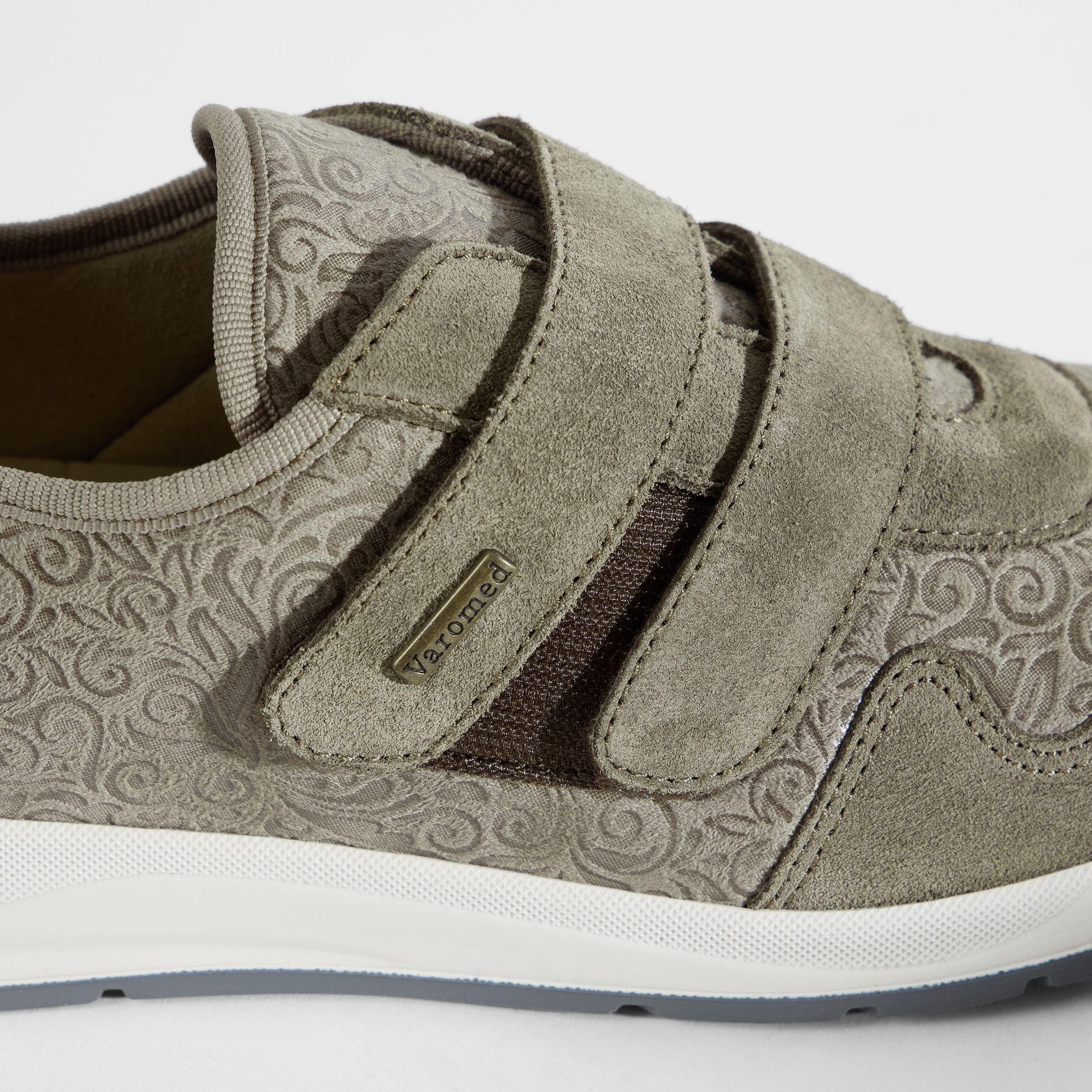 Grauer Damenschuh mit zwei Klettverschlüssen und eingeprägtem Muster.