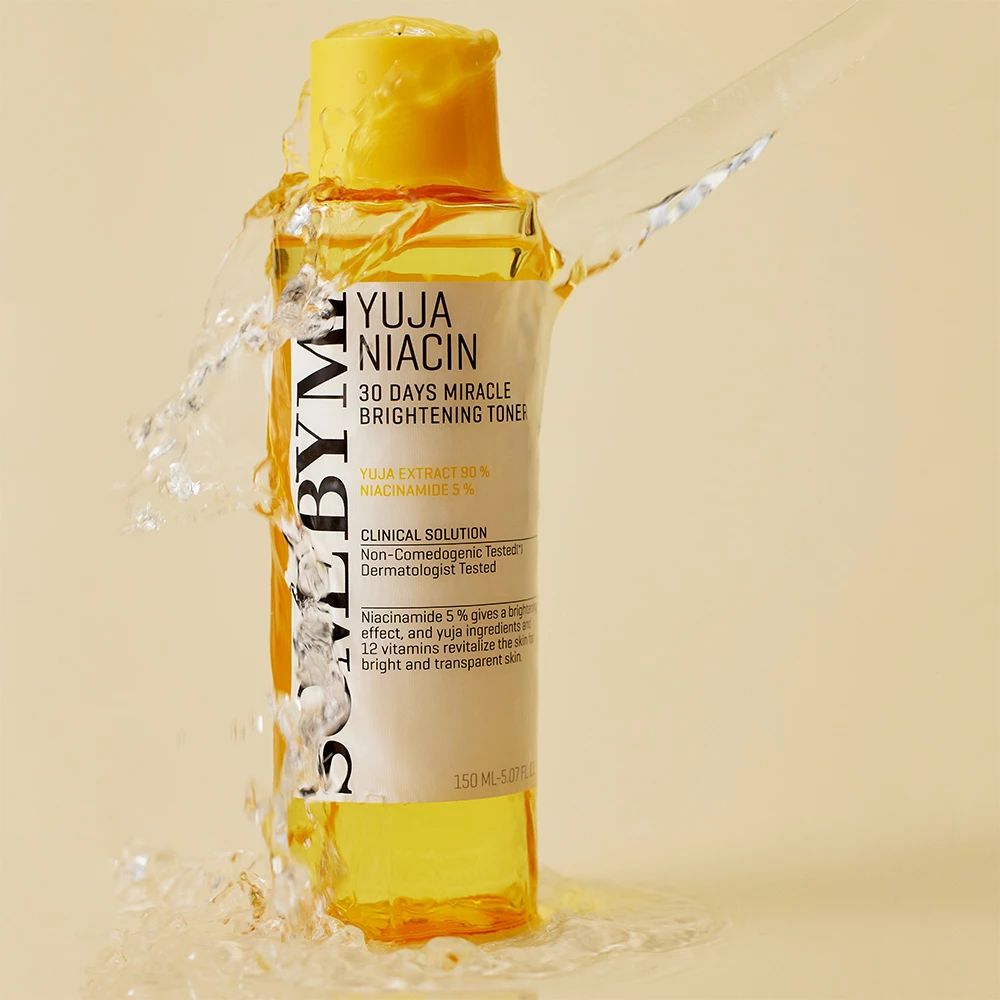Gelbe Flasche mit weißem Etikett. Text: Yuja Niacin, 30 Days Miracle Brightening Toner. Wasser spritzt um die Flasche.