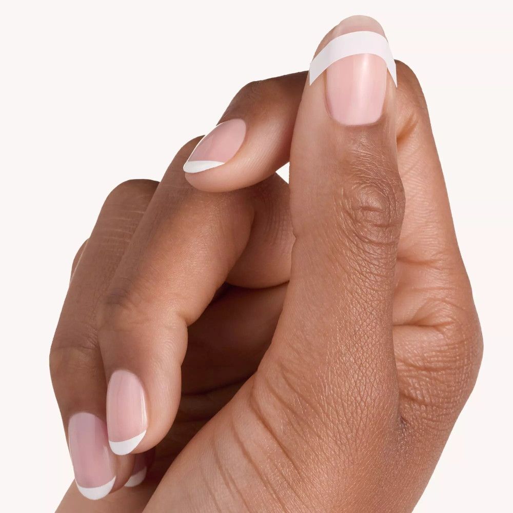 Hand mit French Manicure. Die Nägel sind mit weißem Nagellack lackiert. Ein Finger mit weißem Streifen.
