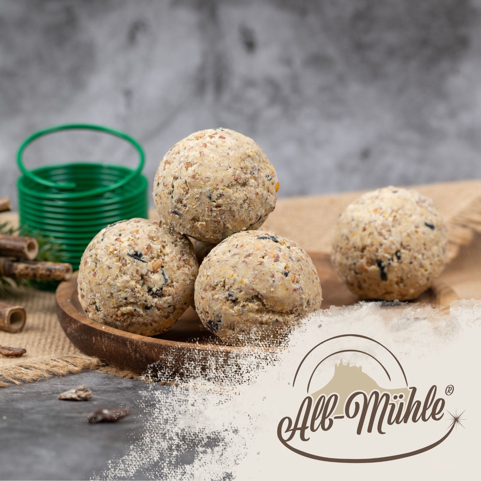 Meisenknödel Vollkorn & Früchte auf einem Holzbrett, All-Mühle Logo.