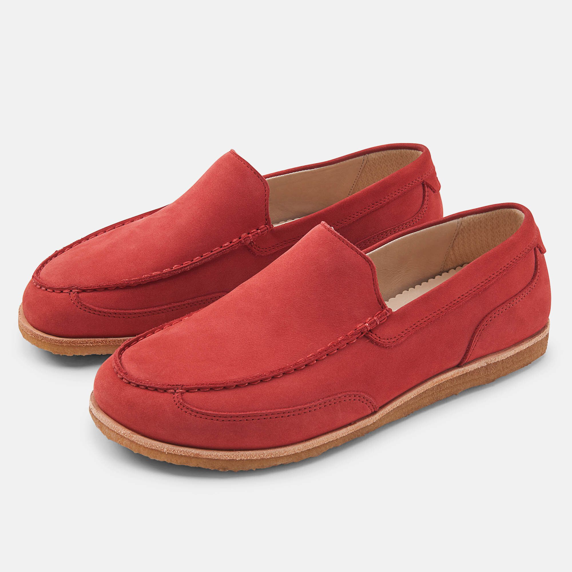 Rote Slipper. Zwei Schuhe nebeneinander. Runde Zehenpartie, helle Sohle, sichtbare Nähte.