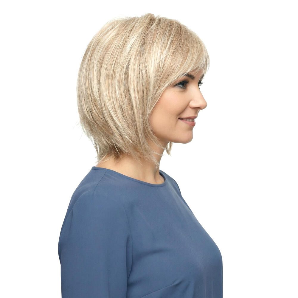 Blond gefärbte Perücke mit kurzem, gestuftem Schnitt. Die Frau trägt ein blaues Oberteil. Seitliche Ansicht.