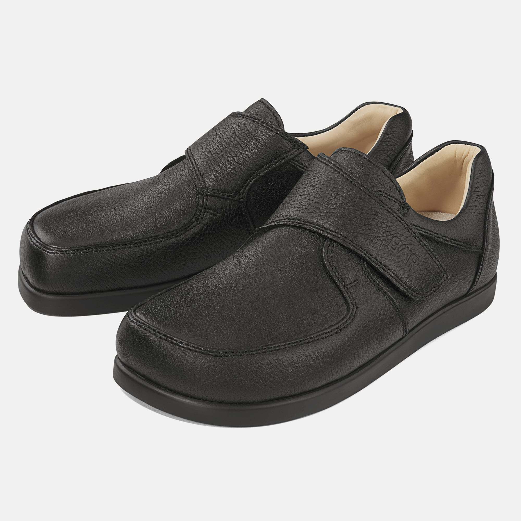 Schwarze Herren-Slipper mit Klettverschluss. BÄR-Logo auf dem Riemen. Breiter Schnitt. Leder-Oberfläche. Hellbraunes Innenfutter.