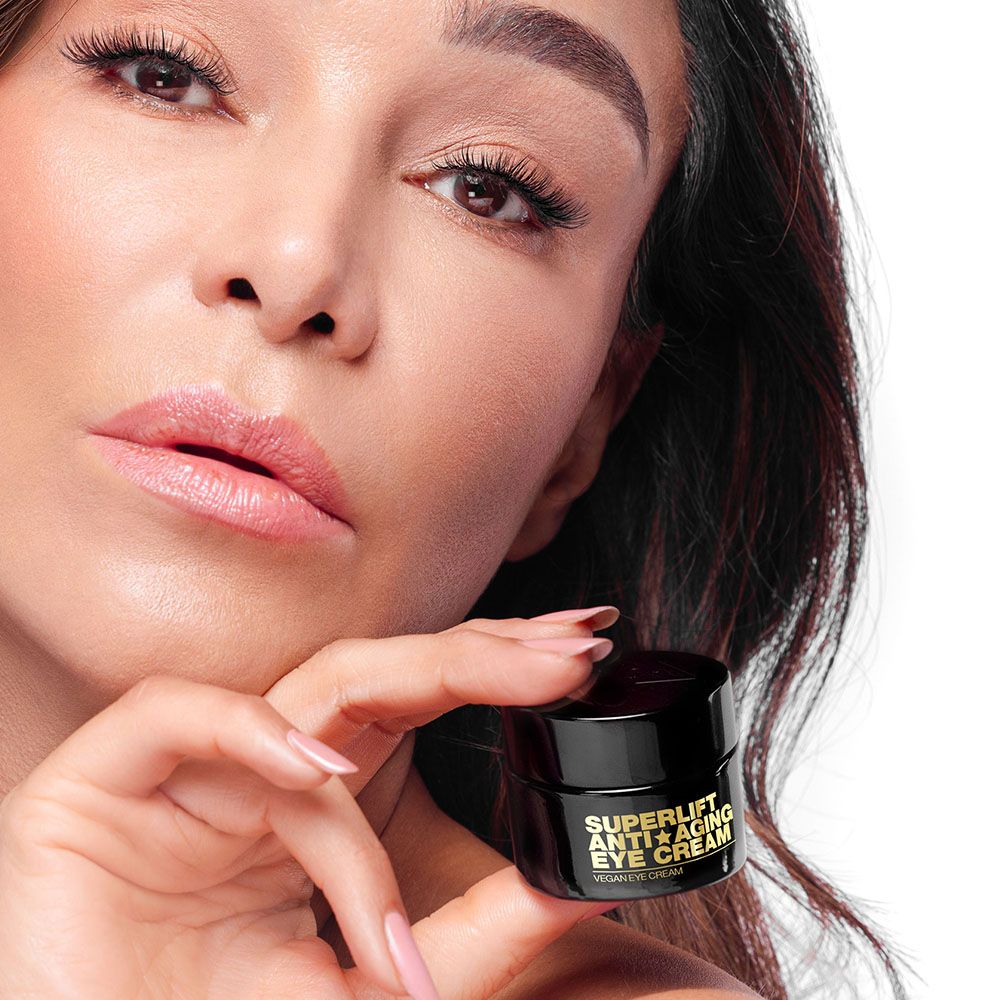 Frau hält einen schwarzen Tiegel mit goldfarbenem Aufdruck: Superlift Anti-Aging Eye Cream.