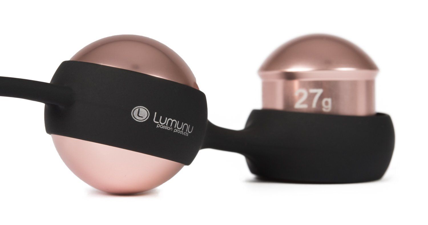 Eine roségoldene Kugel und ein Zylinder mit "27g" Gravur, verbunden durch einen schwarzen Steg. "Lumunu passion products".