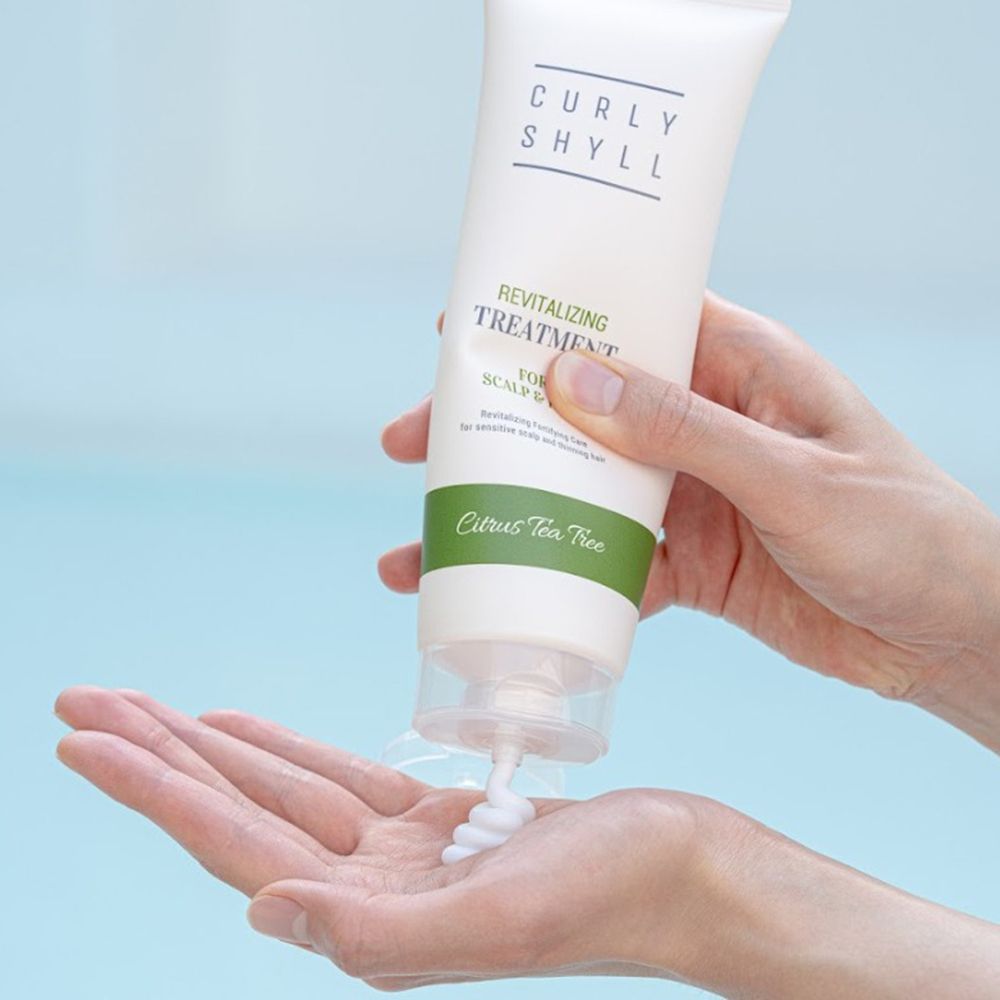 Hände halten eine Tube. Produkt wird herausgedrückt. Text: CURLY SHYLL, Revitalizing Treatment for Scalp & Hair.