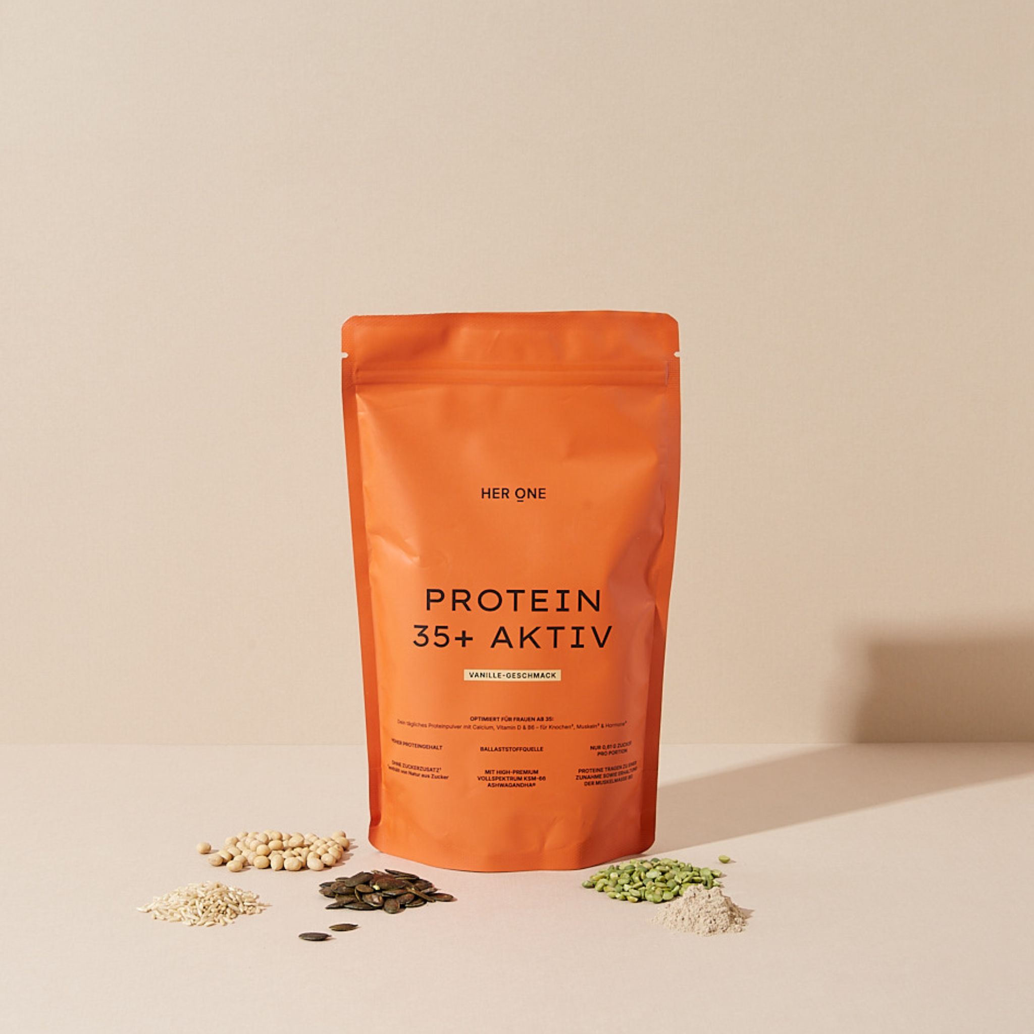 Orangefarbene Verpackung mit HER ONE, PROTEIN 35+ AKTIV. Verschiedene Samen und Körner liegen davor.
