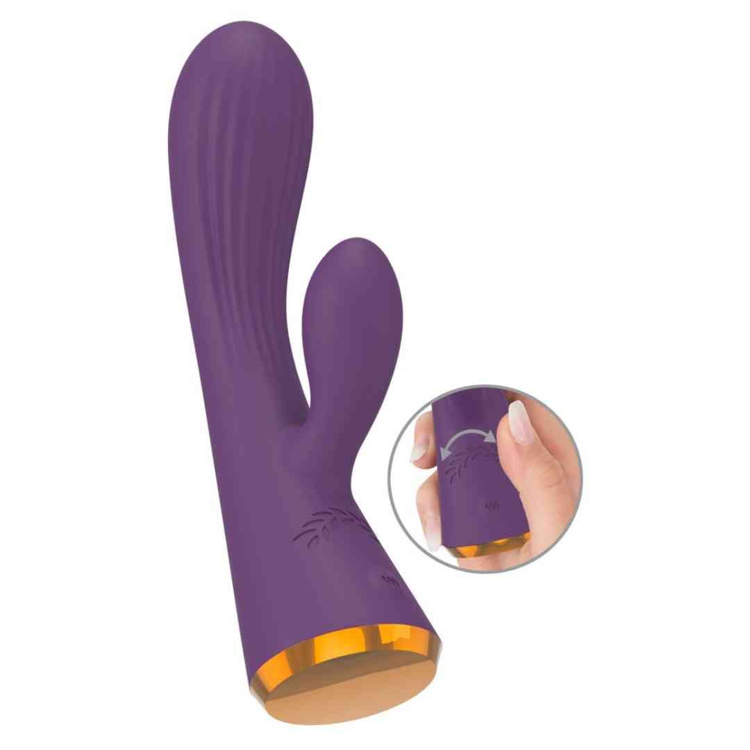 Lila Vibrator mit Hasenohren und geriffelter Oberfläche. Goldfarbener Sockel. Hand zeigt Drehfunktion.