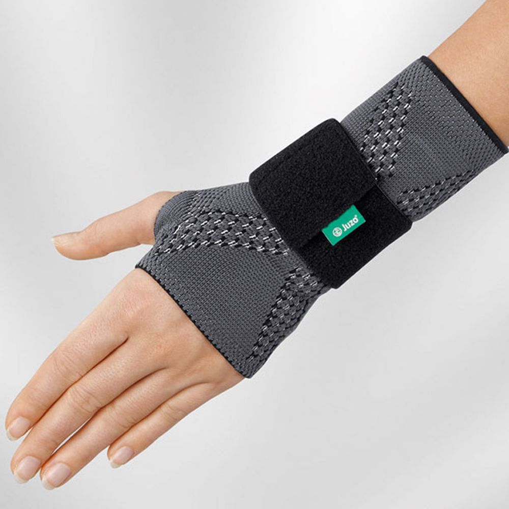 Handgelenkbandage JuzoFlex Manu Xtra, grau mit schwarzem Klettverschluss. Grünes Logo.