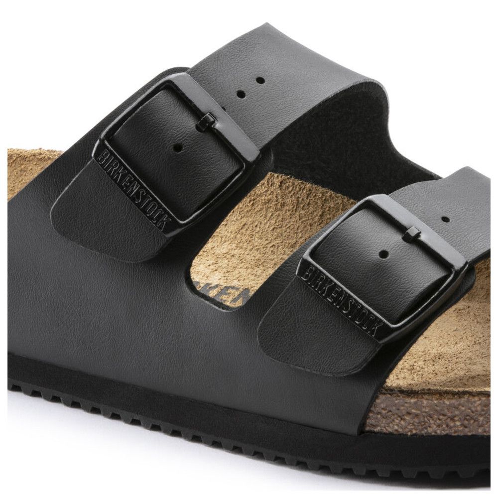 Nahaufnahme einer schwarzen Sandale. Zwei Riemen mit Schnallen. Birkenstock-Logo auf den Schnallen.