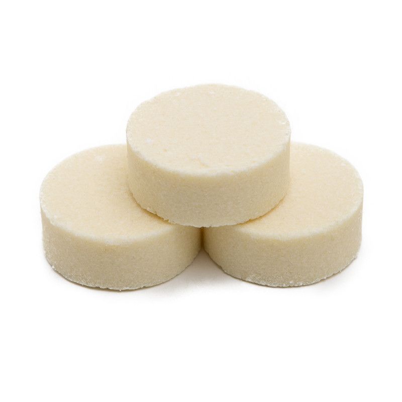 Drei runde, cremefarbene Shampoo-Bars. Sie sind gestapelt, einer oben, zwei unten.