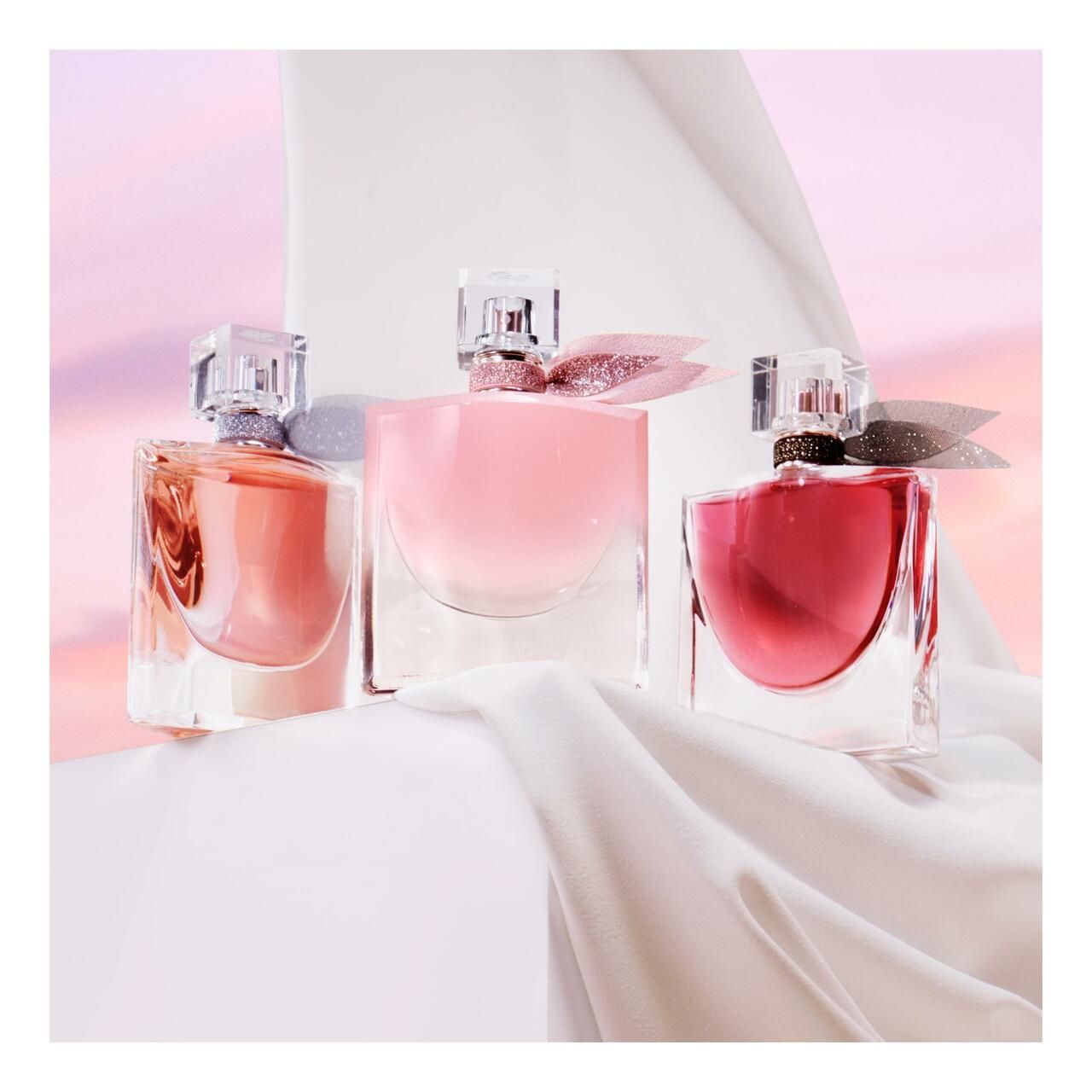 Drei Lancôme La vie est belle Eau de Parfum Flakons in verschiedenen Rosatönen.