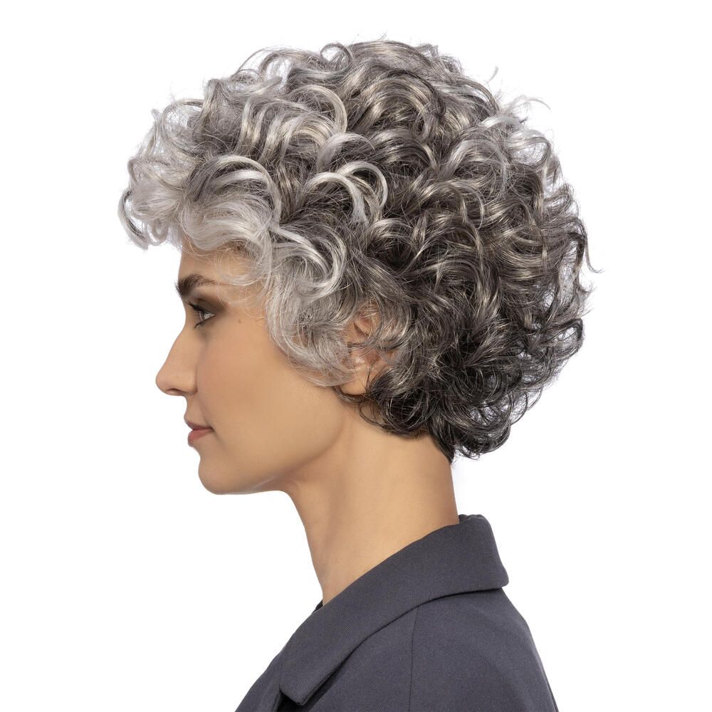 Perücke mit lockigem, grauem Haar. Die Frau trägt einen dunklen Blazer. Profilansicht.