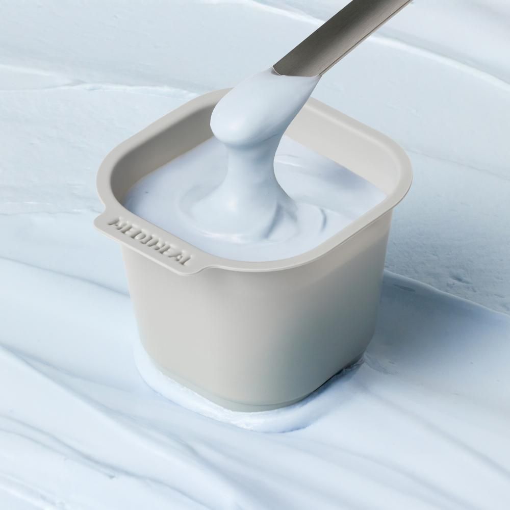 Beige Schale mit hellblauer Creme und Spatel.