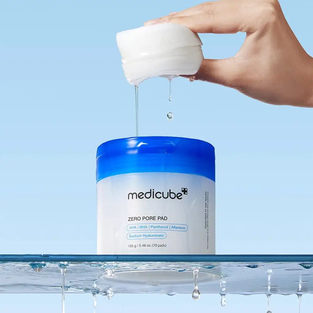 Behälter Medicube Zero Pore Pad mit blauem Deckel. Ein Pad wird gehalten. Wasser tropft. Text: Zero Pore Pad, Inhaltsstoffe. 70 Pads.