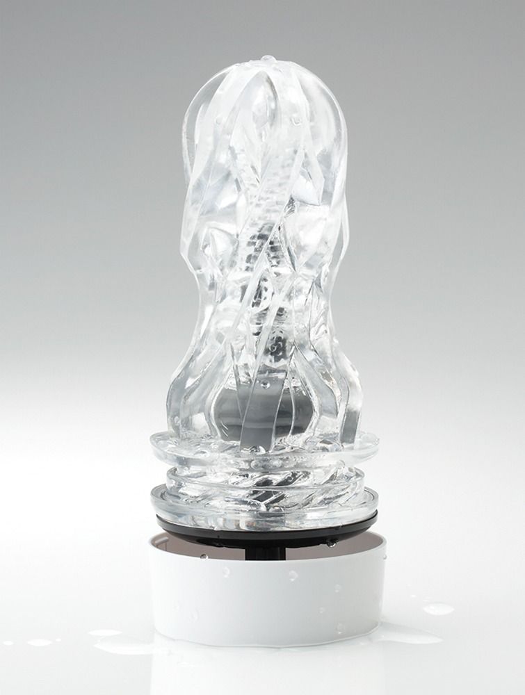 Transparentes Masturbationsgerät mit weißem Sockel. Die innere Struktur ist sichtbar. Das Produkt ist mit Wasser benetzt.