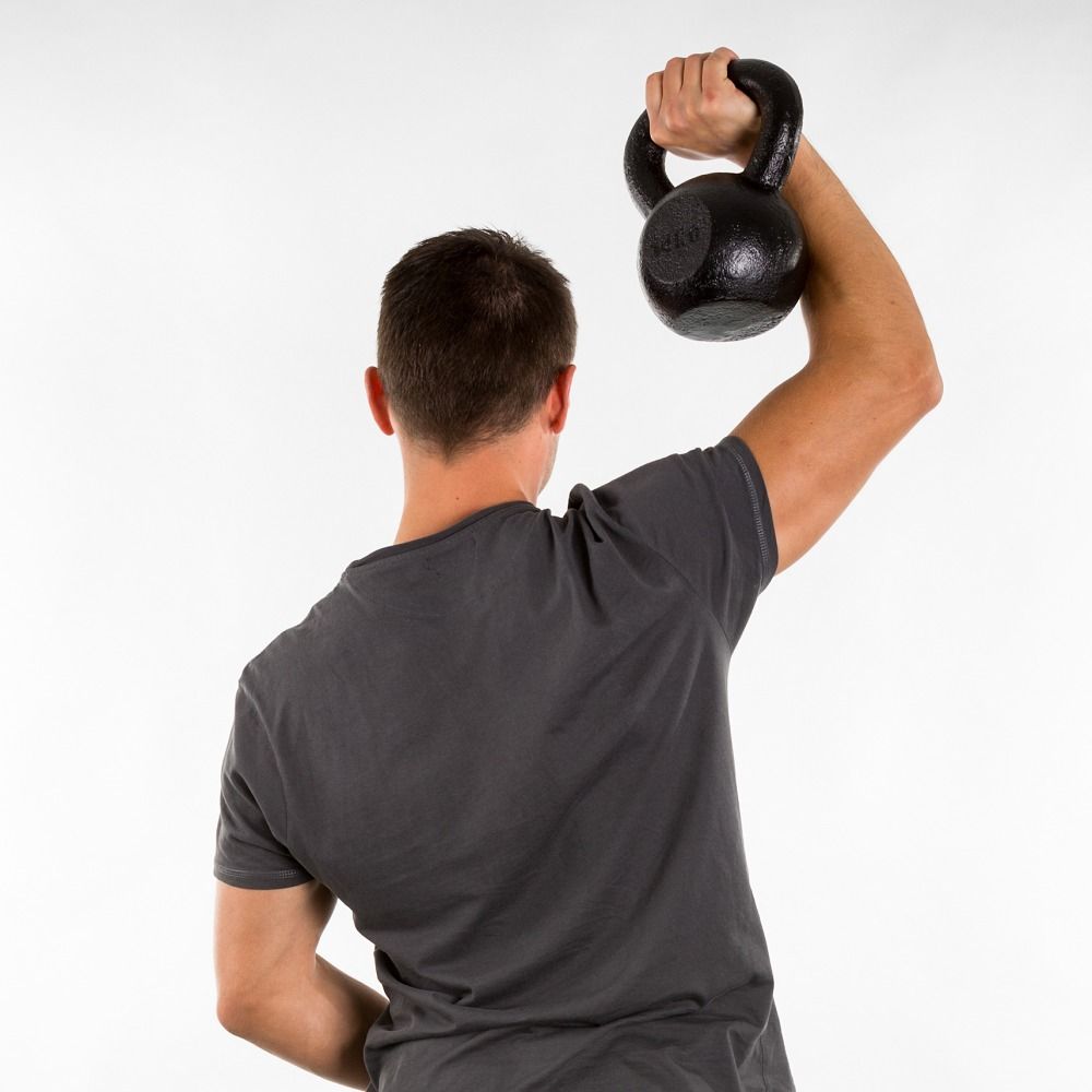 Mann hebt schwarze Kettlebell. Rückansicht. Graues T-Shirt. Weißer Hintergrund.