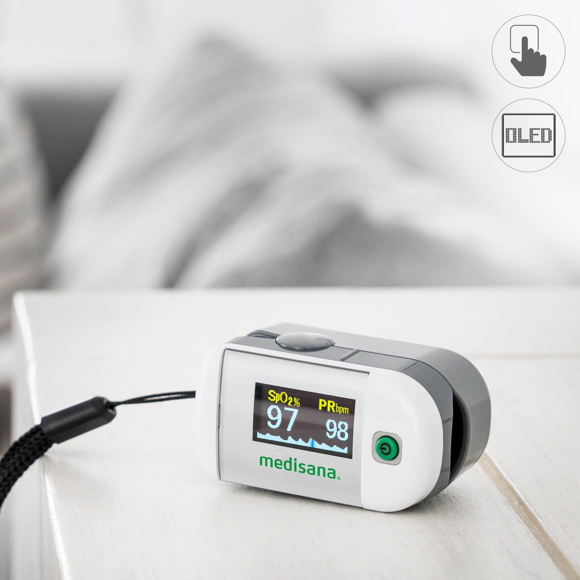 Pulsoximeter op tafel. Toont zuurstofsaturatie en hartslag. Zwarte polsband.