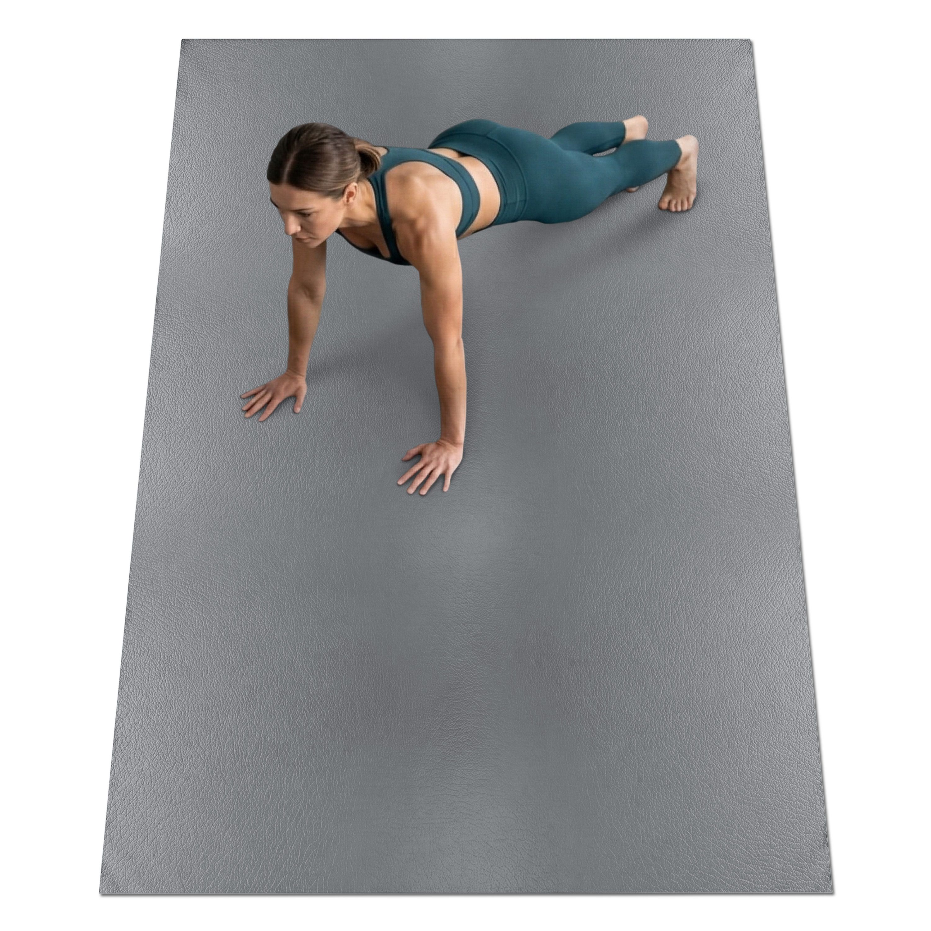 Graue Fitnessmatte, rechteckig, auf dem Boden. Eine Frau macht Liegestütze auf der Matte. Die Matte bedeckt den gesamten Bodenbereich.
