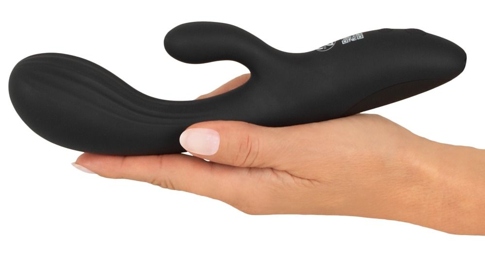 Schwarzer Vibrator in einer Hand gehalten. Gebogene Form mit einem zusätzlichen Teil.