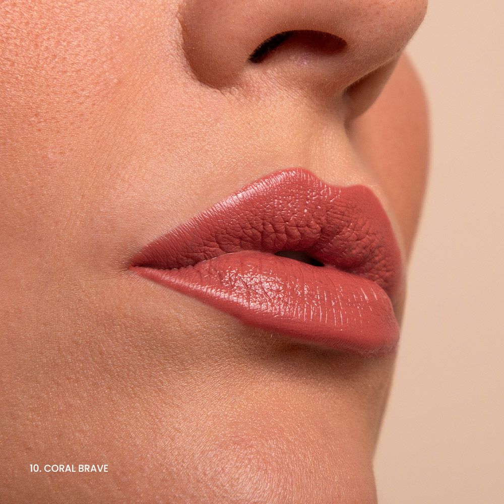 Primo piano di labbra con rossetto color corallo. Testo: 10. Coral Brave.