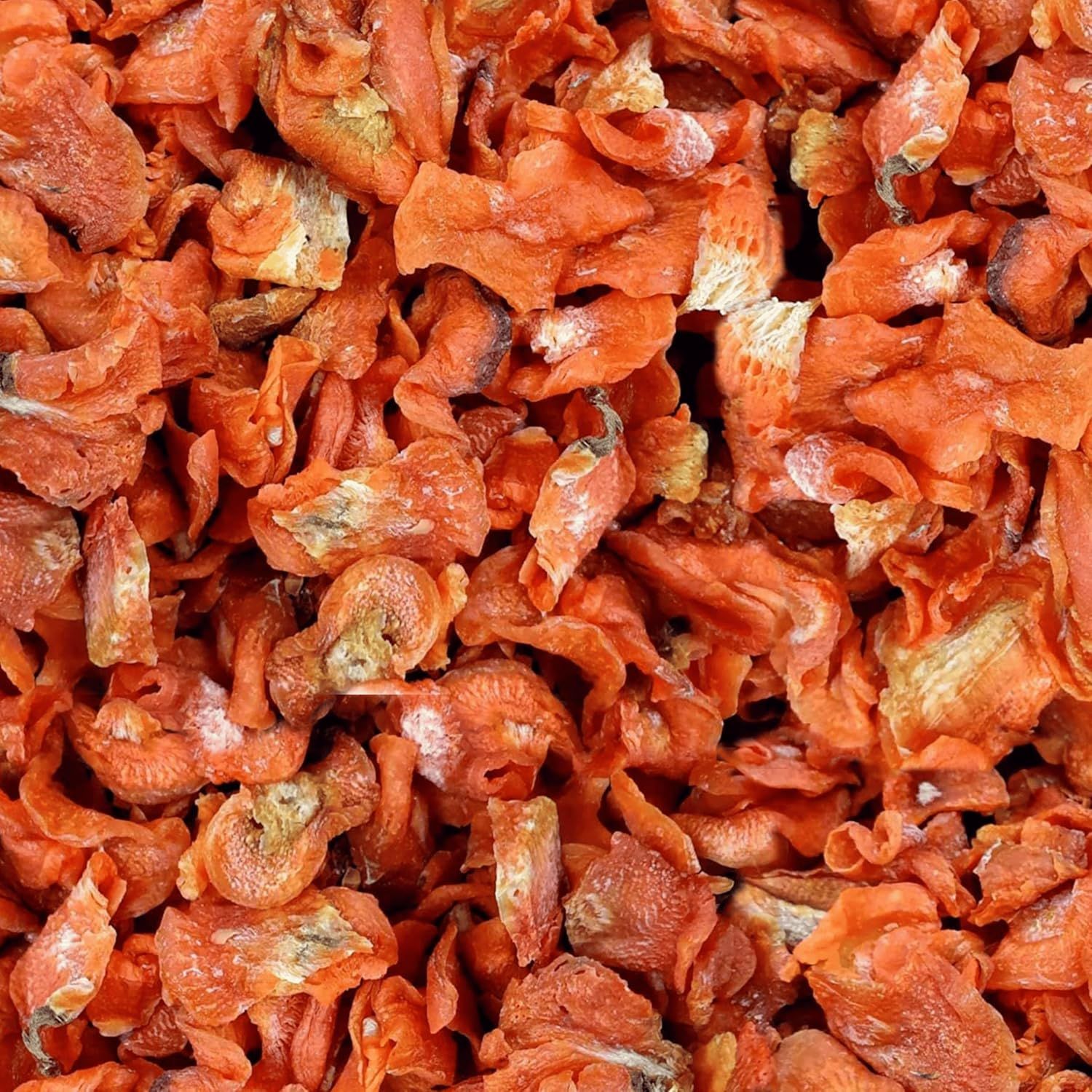 Getrocknete Karottenchips. Orangefarbene, unregelmäßig geformte Stücke. Nahaufnahme, Textur sichtbar.