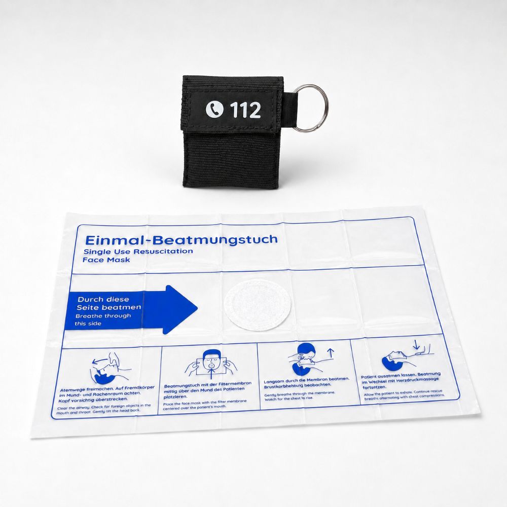 Kleiner Beutel mit Notrufnummer 112 und Schlüsselring neben einer Packung Beatmungstücher.