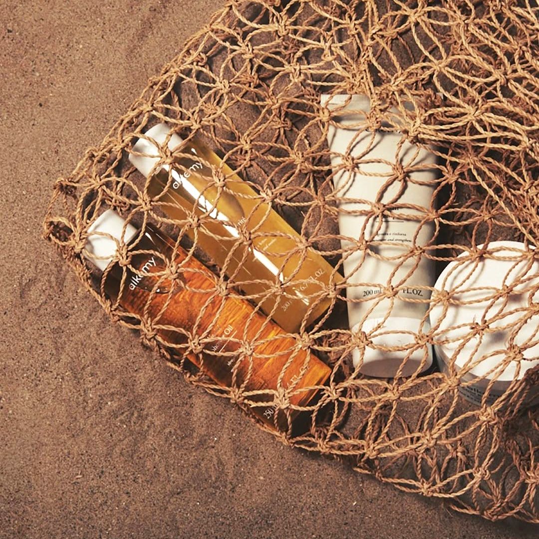 Eine Tasche mit Alkemy Produkten am Strand.