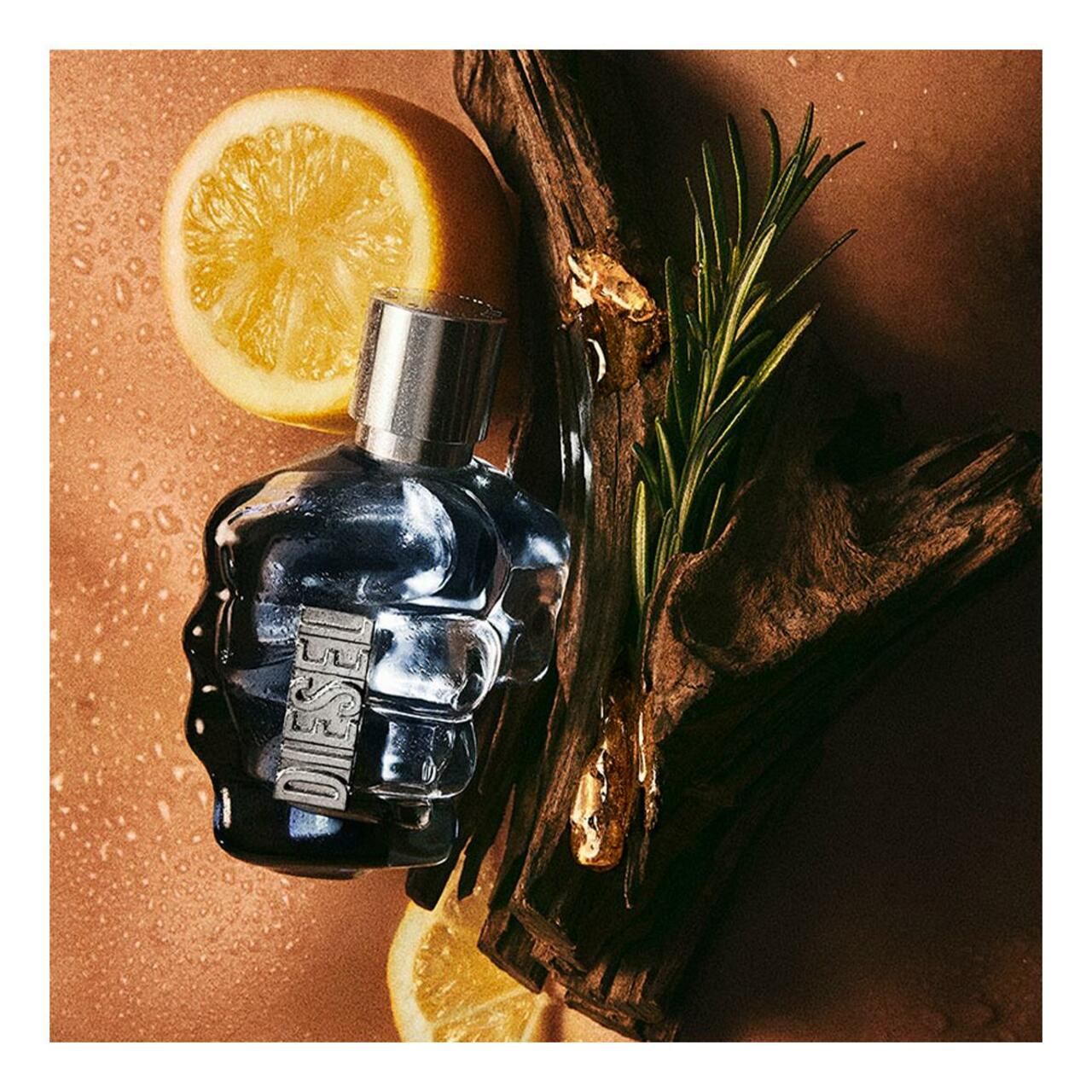 Flakon in Faustform, daneben Zitrone, Holz und Rosmarin. Flakon mit silbernem Verschluss.