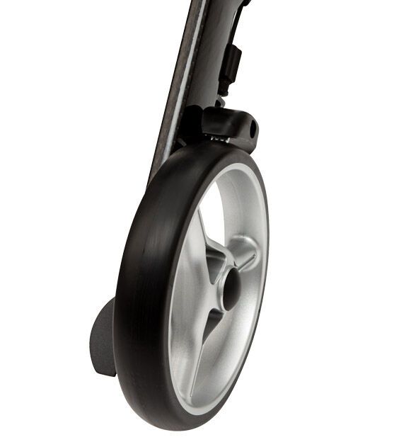 Nahaufnahme eines Rollator-Rades. Schwarzer Reifen mit silberner Felge. Teil des Rahmens sichtbar.