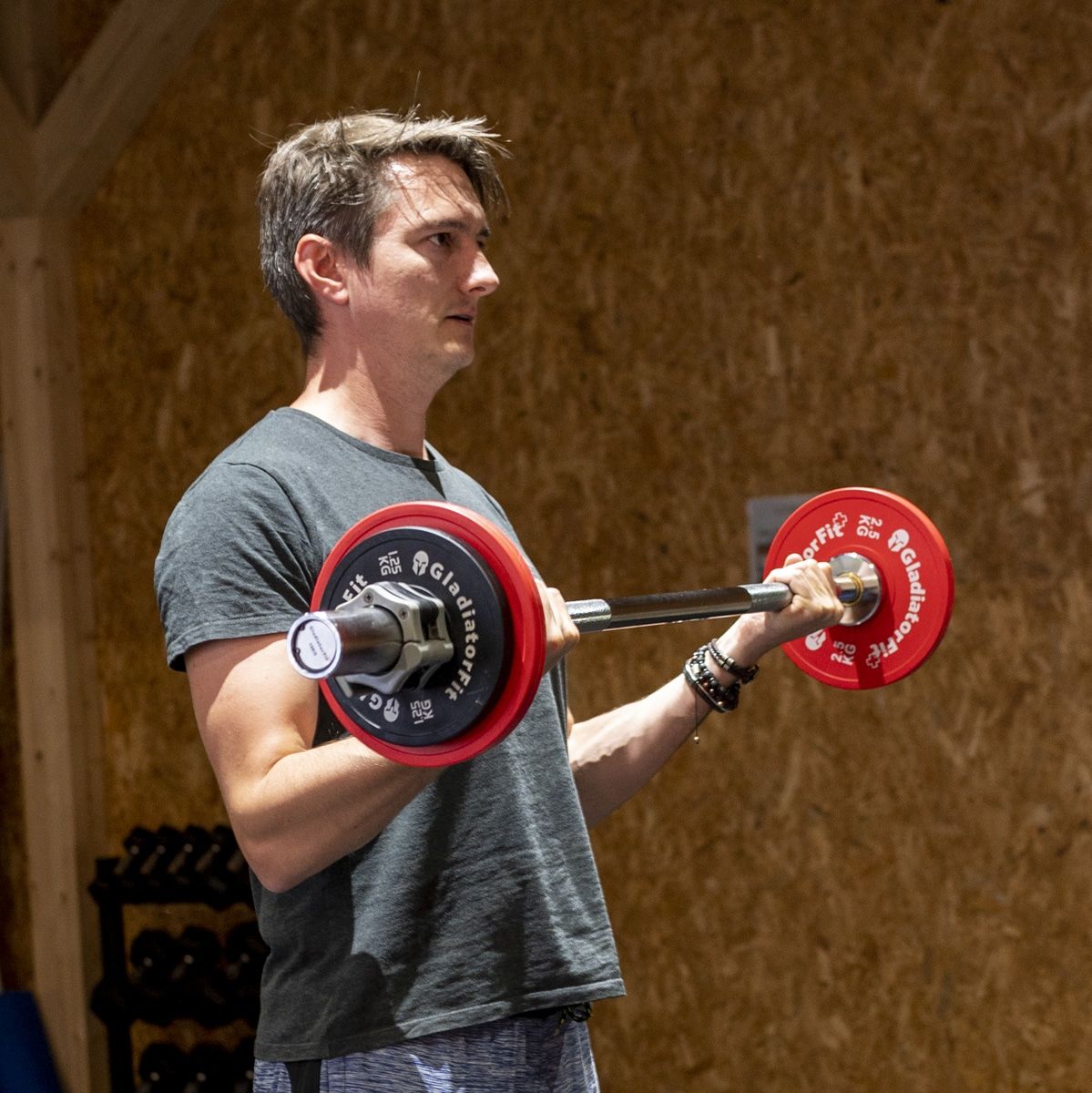 Mann trainiert mit Hantelstange und roten Gewichtsscheiben. Im Fitnessstudio.