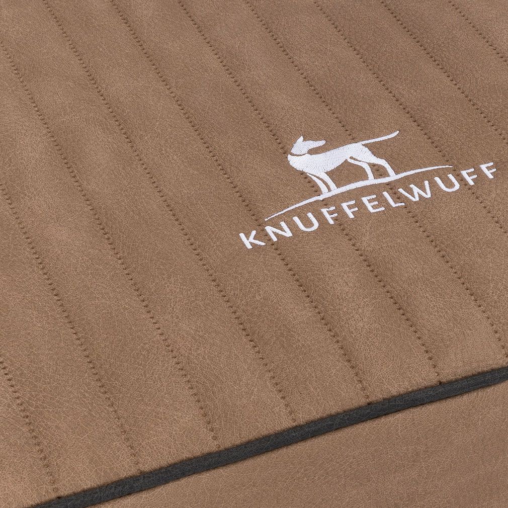 Detailansicht der orthopädischen Hundematte Palomino. Braunes Material, Logo Knuffelwuff, schwarzer Rand, Steppnähte.