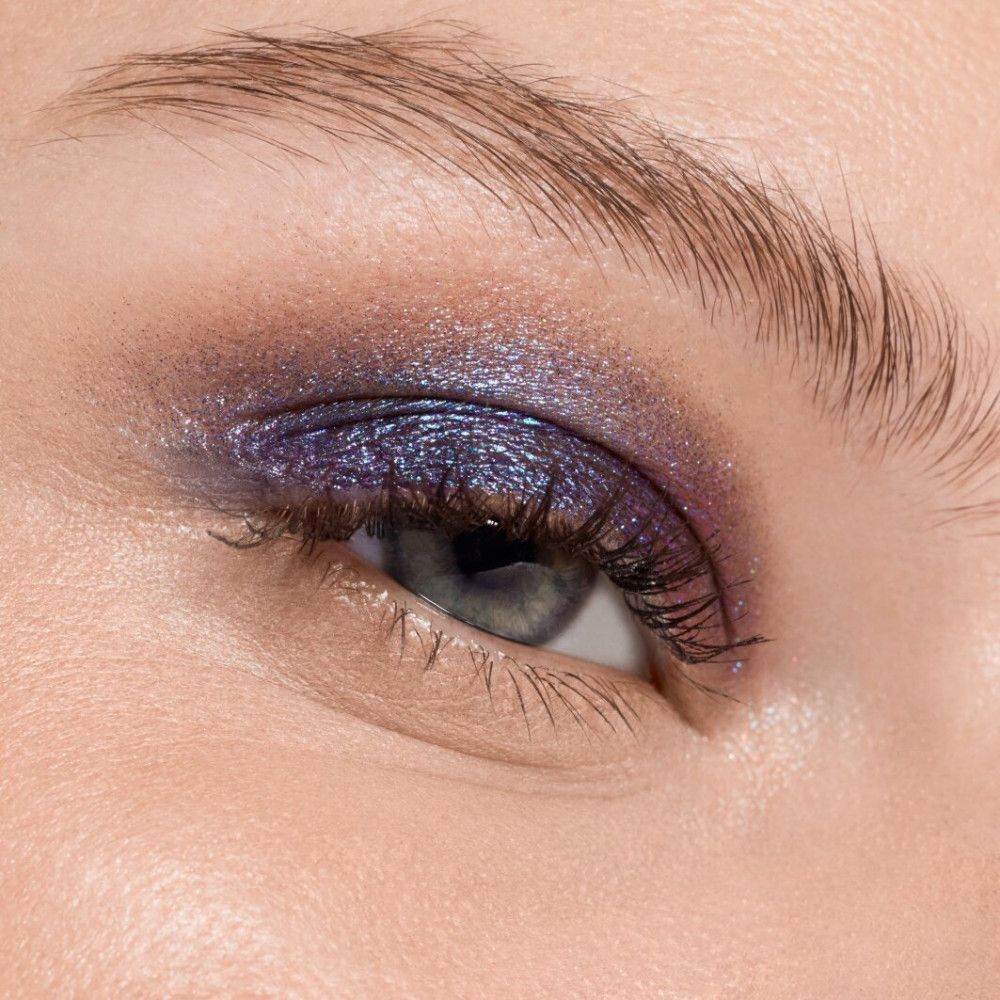 Nahaufnahme eines Auges mit blau-violettem Lidschatten. Der Lidschatten ist auf dem gesamten Augenlid aufgetragen.