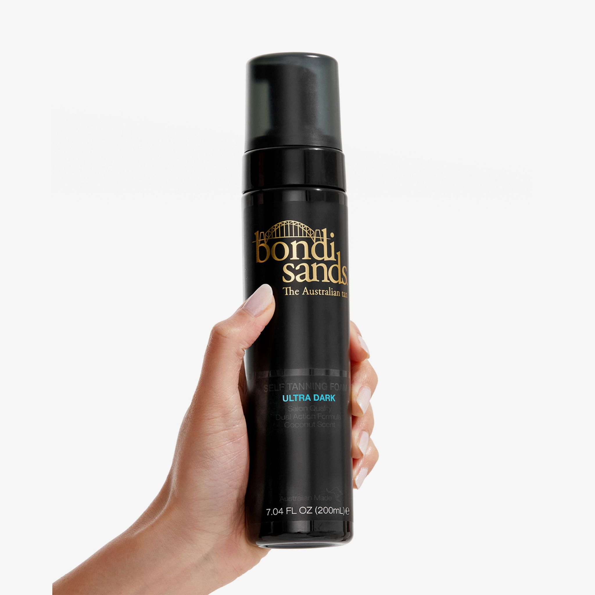 Main tenant un flacon noir avec logo Bondi Sands et texte 'Ultra Dark'. Contient 200 ml de mousse autobronzante.