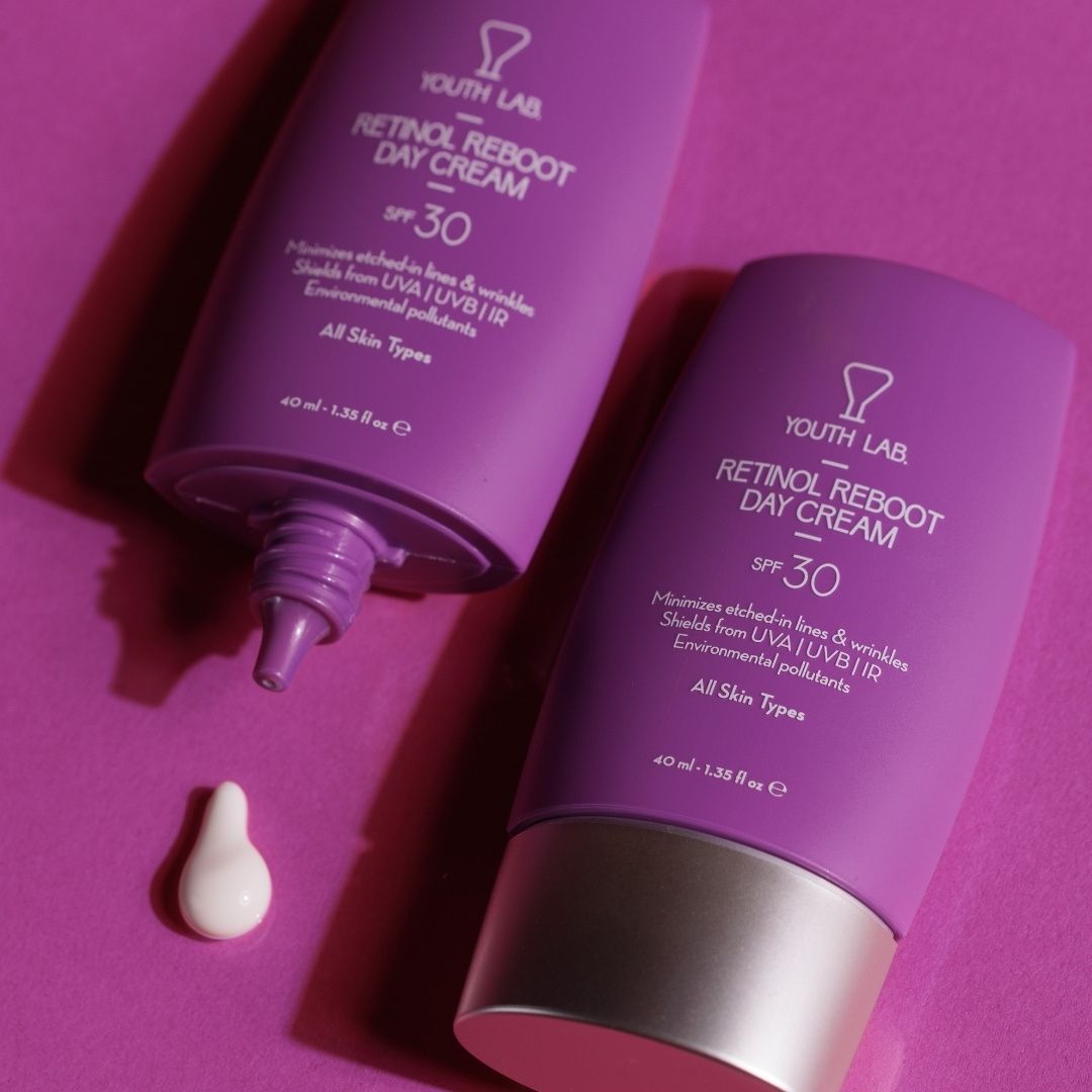 Zwei lila Tuben. Aufschrift: YOUTH LAB Retinol Reboot Day Cream SPF 30. Eine Tube geöffnet, Creme sichtbar.