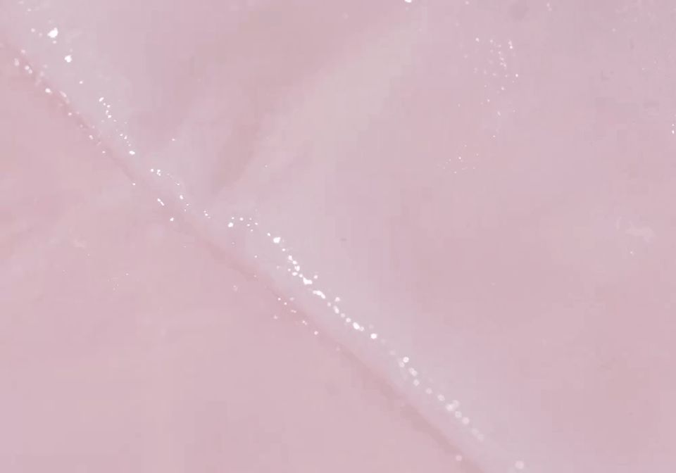 Nahaufnahme einer feuchten, rosa Tuchmaske mit glitzernden Partikeln.
