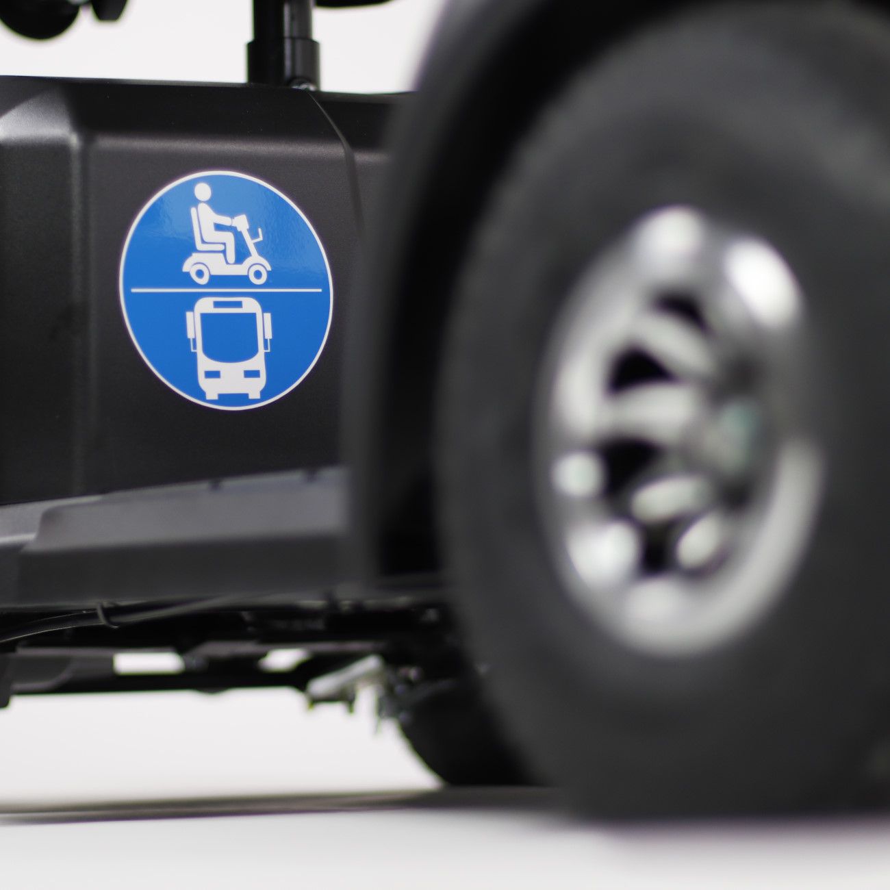 Detailansicht eines Elektromobils. Blaues Symbol für Rollstuhlfahrer und Bus. Schwarzer Rahmen und ein Rad.