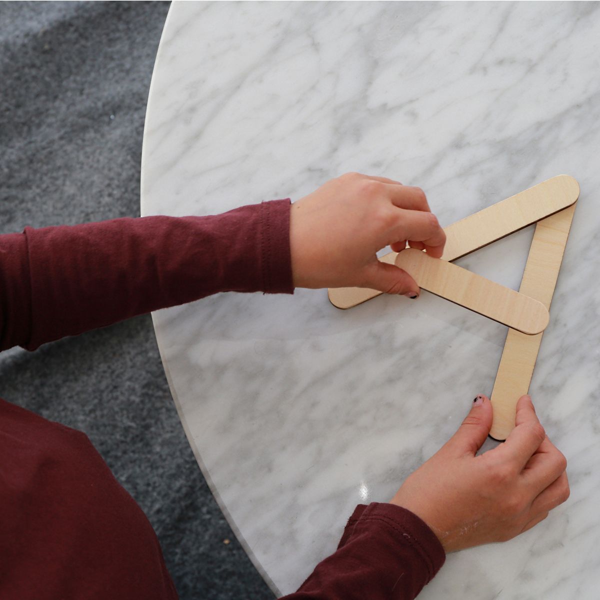 Kind hält Holzbuchstaben A. Kind hält Holzbuchstaben A. Tischplatte aus Marmor. Kind hält Holzbuchstaben A.