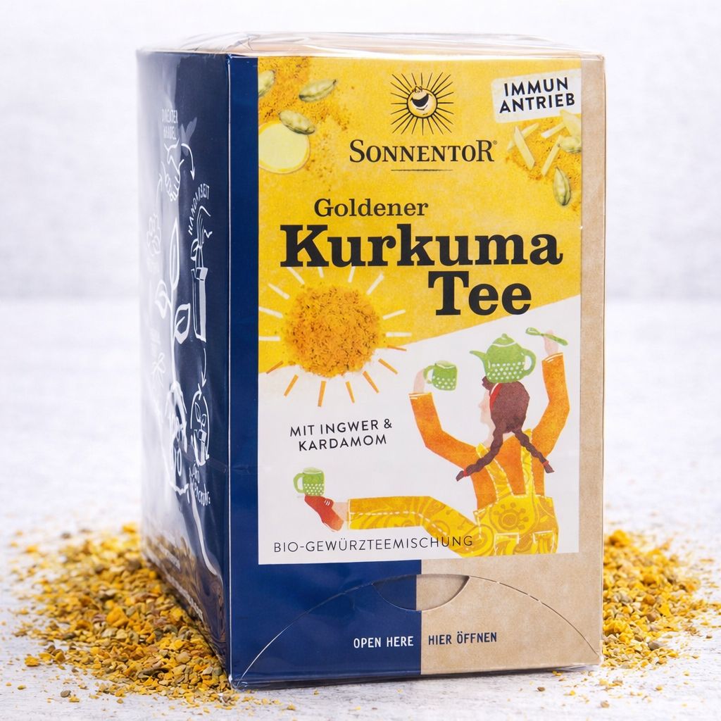 Sonnentor Goldener Kurkuma Tee Packung mit verstreutem Tee und einer Tasse dampfenden Tees.