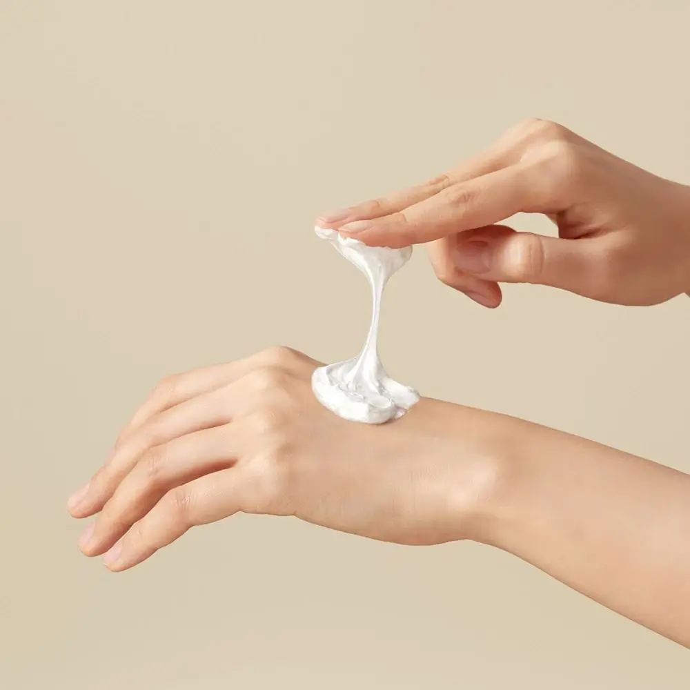 Hände mit weißem Reinigungsschaum auf der Handfläche. Schaum wird von einer Hand aufgetragen.