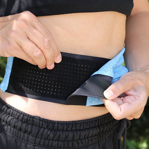 Person hält einen blauen Bauchgurt. Schwarze Platte mit Löchern.