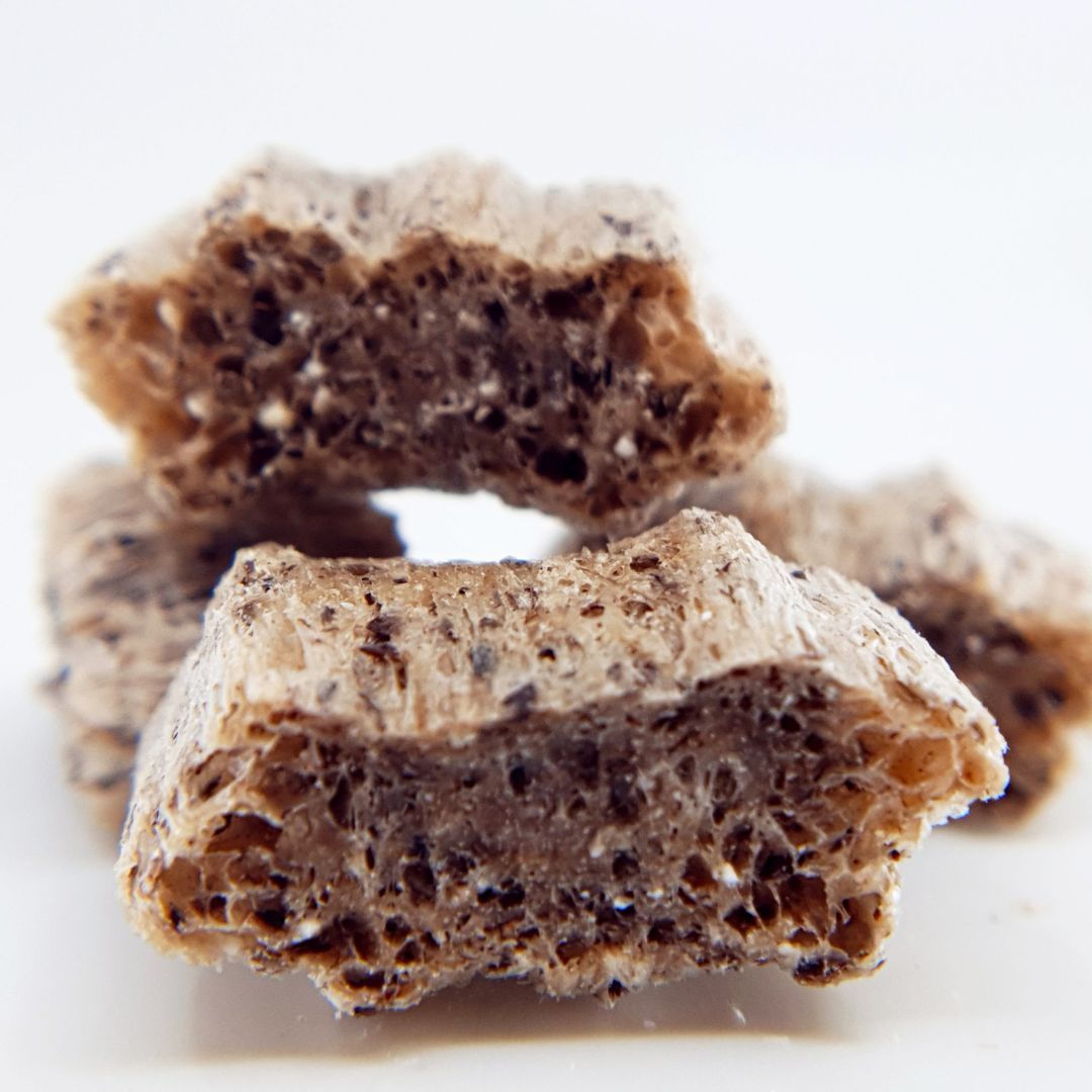 Nahaufnahme von QCHEFS Puffies. Eckige, bräunliche Stücke mit poröser Textur. Einige Stücke sind angeschnitten und zeigen die innere Struktur.