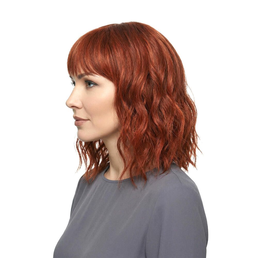 Rote Perücke mit Pony. Die Frau trägt ein graues Oberteil. Seitenansicht.