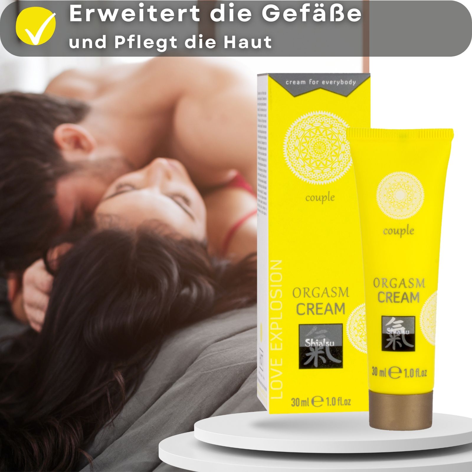 Gelbe Tube und Schachtel. Aufschrift: ORGASM CREAM, Shiatsu, 30 ml. Paar im Hintergrund.