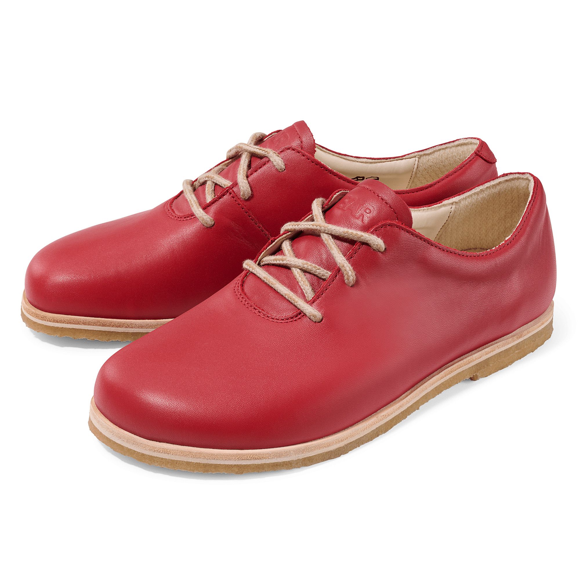 Rote Schnürschuhe. Hellbraune Schnürsenkel. Helle Sohle. Zwei Schuhe nebeneinander.