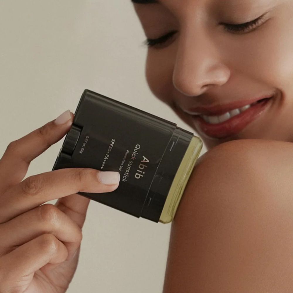 Frau trägt ABIB Quick Sunstick Protection Bar auf ihre Schulter auf.