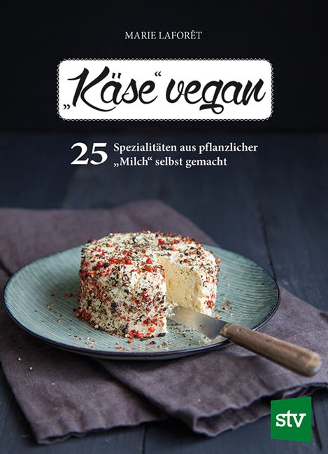Buchcover: „Käse vegan“. Runde Käsespezialität mit Gewürzen auf Teller. Messer daneben. Titel und Autor sichtbar.