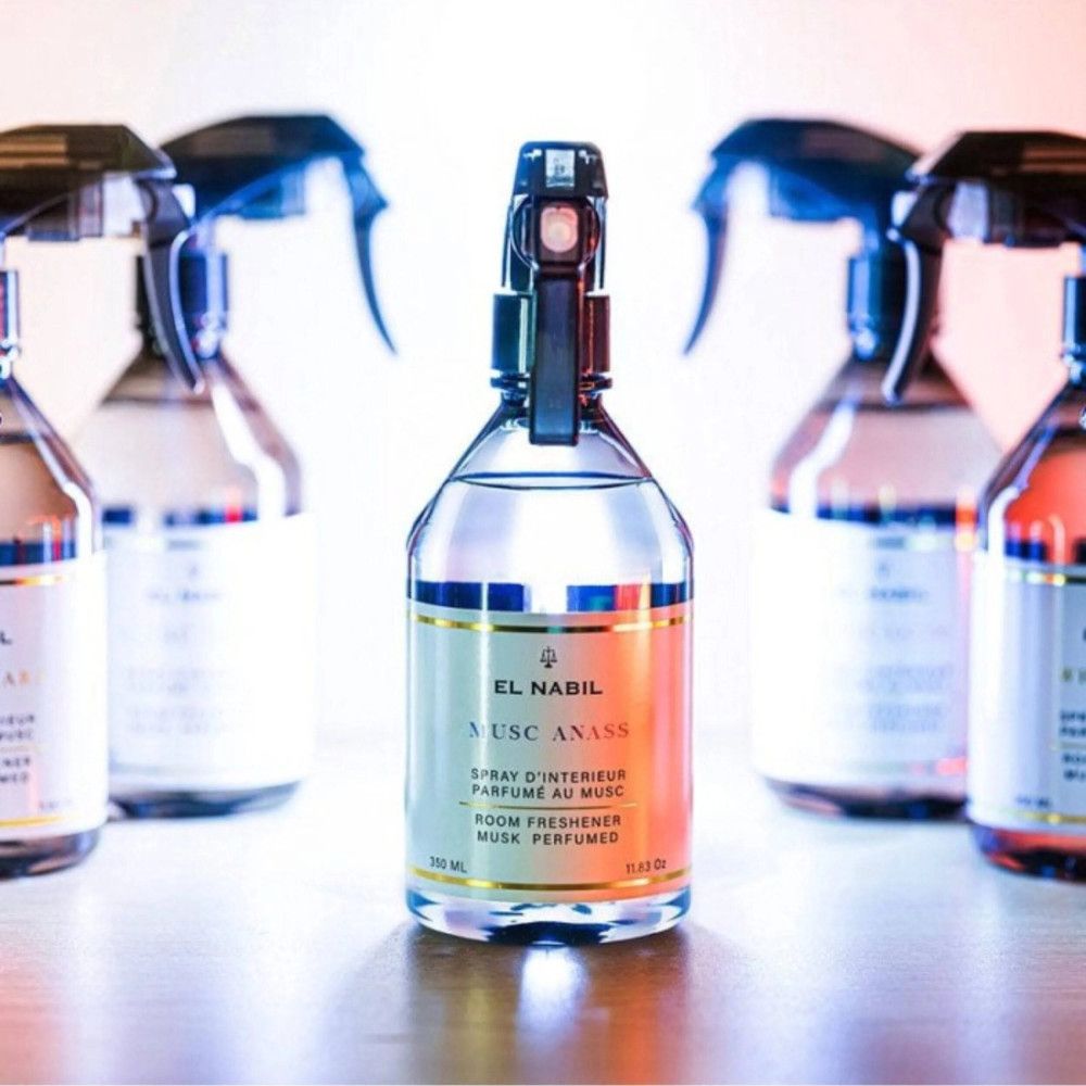 Mehrere Sprühflaschen, El Nabil Anass Musk Raum Spray. Klare Flaschen mit schwarzem Sprühkopf, goldfarbenem Etikett und Produktbezeichnung.